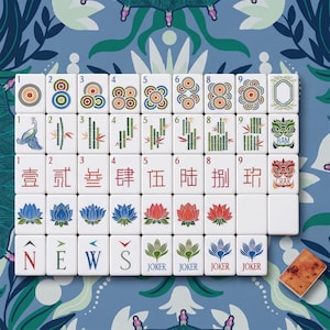 Puede incluir: Un conjunto de fichas de mahjong blancas dispuestas en cuadr&iacute;cula, con ilustraciones coloridas de c&iacute;rculos, bamb&uacute;, caracteres chinos, flores de loto y las letras direccionales N, E, W, S. Incluye cuatro fichas de comod&iacute;n y una ficha marr&oacute;n.
