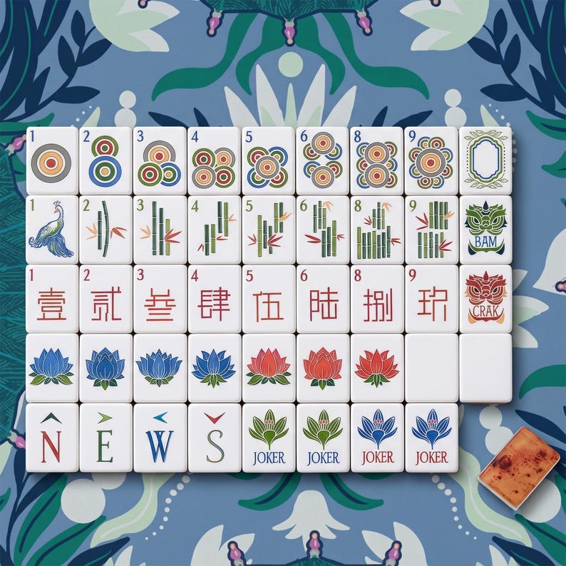 Puede incluir: Un conjunto de fichas de mahjong blancas dispuestas en cuadr&iacute;cula, con ilustraciones coloridas de c&iacute;rculos, bamb&uacute;, caracteres chinos, flores de loto y las letras direccionales N, E, W, S. Incluye cuatro fichas de comod&iacute;n y una ficha marr&oacute;n.