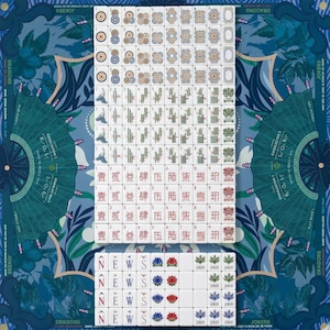 Puede incluir: Un juego de fichas de Mahjong dispuesto sobre una alfombrilla azul con motivos. Las fichas presentan varios palos, incluidos c&iacute;rculos, bamb&uacute;, caracteres, vientos, flores y comodines. La alfombrilla muestra gr&aacute;ficos en abanico y texto.