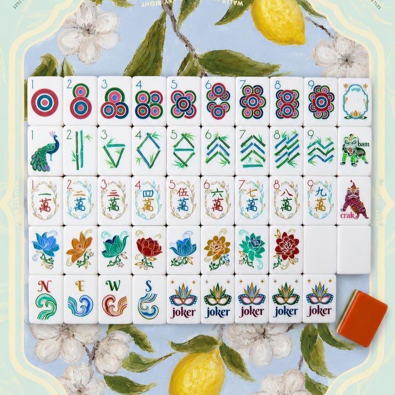 May include: A complete set of white Mahjong tiles featuring colorful illustrations of circles, bamboo sticks, Chinese characters, flowers, and joker masks. The tiles are arranged in a grid, with one orange tile placed separately at the bottom right.