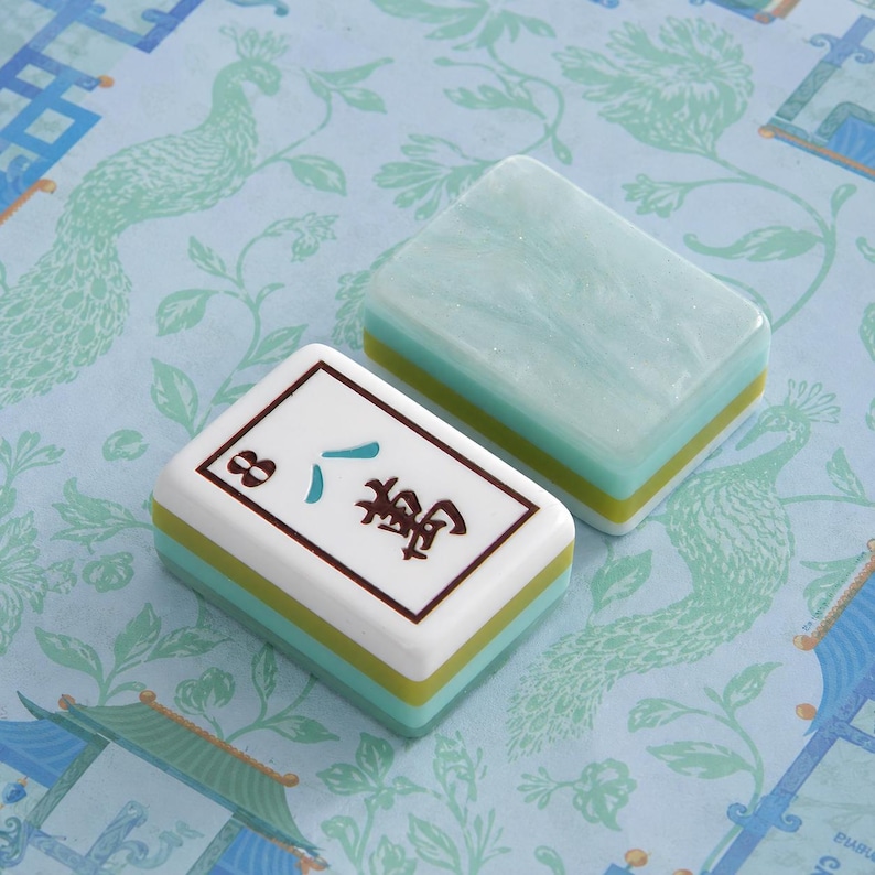 Puede incluir: Dos fichas de mahjong rectangulares con un dise&ntilde;o en capas que presenta una parte superior blanca, una fina capa intermedia verde lima y una base verde azulado. Una ficha muestra el car&aacute;cter chino para ocho y el n&uacute;mero 8, la otra es jaspeada.