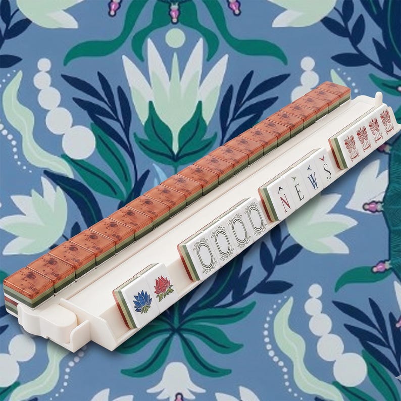 Puede incluir: Un soporte de pl&aacute;stico blanco para fichas de mahjong con una fila de fichas marrones estampadas y una fila frontal de fichas blancas. Las fichas frontales muestran la palabra NEWS en letras negras, cuatro marcos ovalados y dos flores de loto.