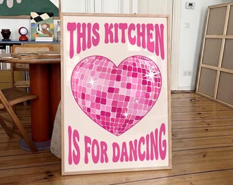 Könnte beinhalten: Ein rechteckiges gerahmtes Wandbild mit hellcremefarbenem Hintergrund. Es zeigt in der Mitte eine große, herzförmige, rosa Discokugel-Grafik mit weißen Sternakzenten. Der Text THIS KITCHEN IS FOR DANCING ist in Rosa aufgedruckt.