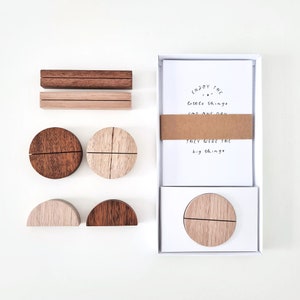 May include: Wooden desk accessories set. Includes two rectangular holders, two circular holders, and two semi-circular holders. A box of cards with the text "Enjoy the little things for one day, they were the big things" is also included.