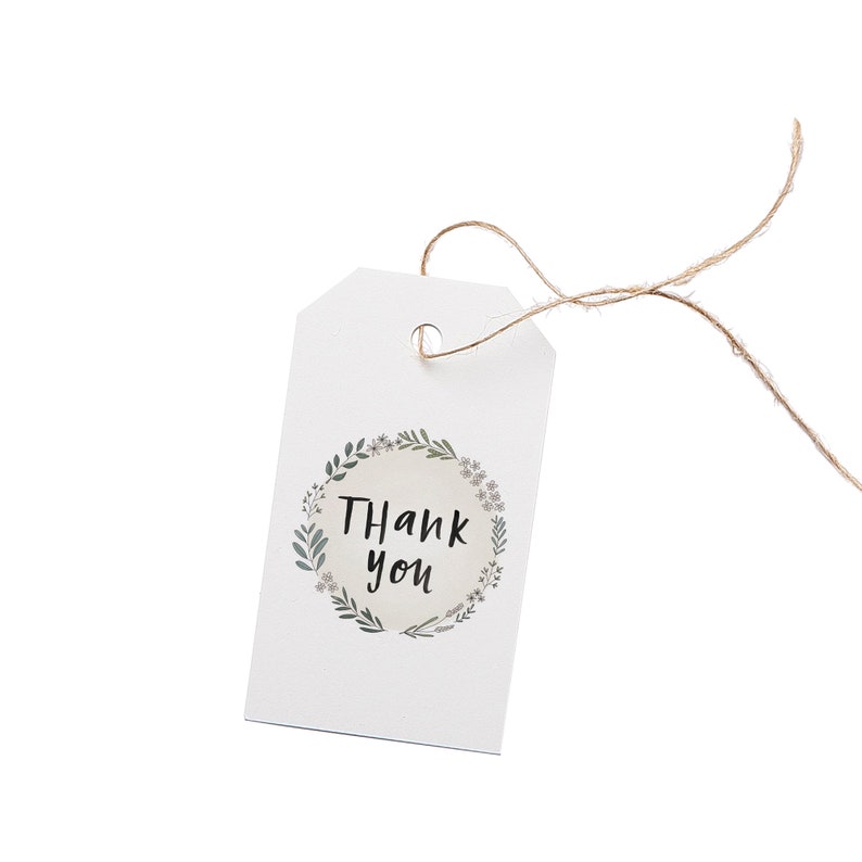 May include: A white gift tag with a floral wreath design and the words "Thank you" in black script. The tag is attached to a natural twine string, perfect for adding a personal touch to gifts or favors.