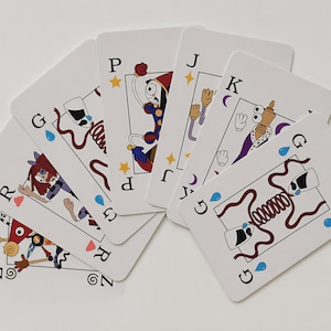 Pode incluir: Um leque de seis cartas de baralho com fundo branco e ilustrações coloridas de desenhos animados. As cartas apresentam vários personagens e símbolos, incluindo as letras G, P, J, K, R e Z, junto com pequenos ícones de gotas azuis e estrelas amarelas.
