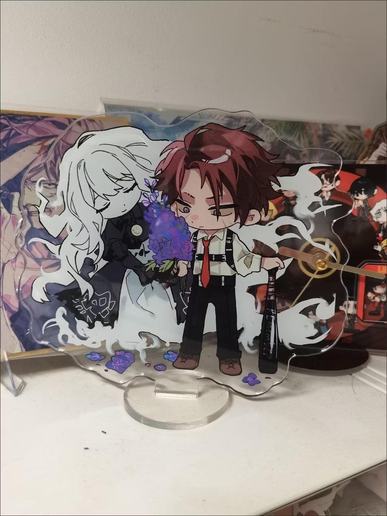 May include: A clear acrylic standee featuring a chibi-style illustration of a person with reddish-brown hair holding a bouquet of purple flowers and a black baseball bat, accompanied by a ghostly white-haired figure in a dark outfit.