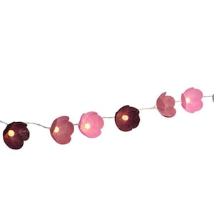 May include: A string of decorative flower-shaped lights in shades of pink and burgundy. Each flower has a small, warm-toned light in the center. The lights are strung on a thin, silver wire, creating a whimsical and festive look.