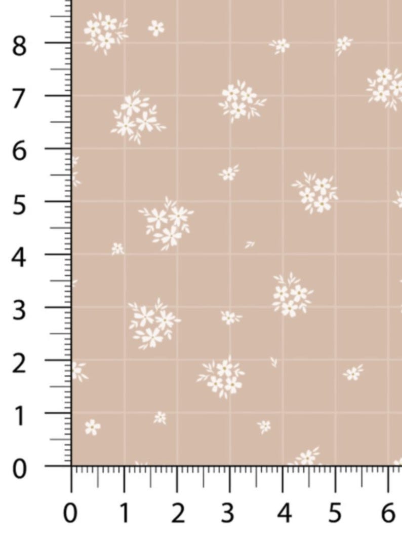 May include: Tan fabric with a grid pattern and scattered white floral clusters. The grid is marked with measurements in inches, with numbers from 0 to 8 along the left edge and 0 to 6 along the bottom edge.
