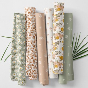 May include: Rolled fabric bolts in various floral patterns. Designs include daisies, small flowers, and larger blooms in shades of green, brown, peach, and white. The fabrics are arranged vertically against a white background.