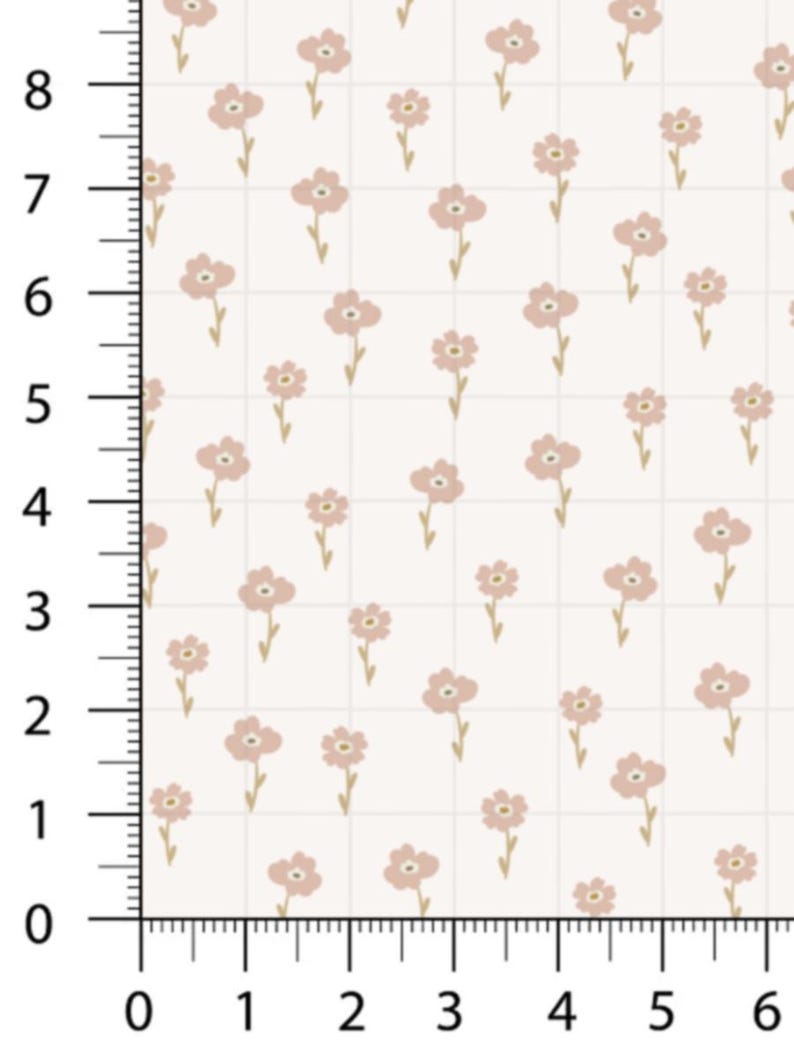 May include: A fabric sample featuring a repeating floral pattern. The design showcases small, light pink flowers with yellow centers and stems, evenly spaced on a cream-colored background. The grid-like pattern is marked with a ruler showing measurements in inches.