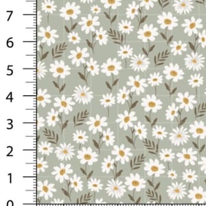 May include: A fabric pattern featuring white daisies with yellow centers and brown stems and leaves on a light green background. The pattern is arranged in a grid, with measurements in inches along the side.