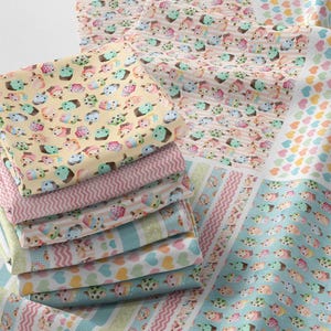 Puede incluir: Una pila de cuadrados de tela coloridos con varios patrones. Los patrones incluyen cupcakes, corazones y rayas en colores pastel como rosa, azul, amarillo y verde. La tela es probablemente de algodón o un material similar, adecuado para proyectos de acolchado o manualidades.