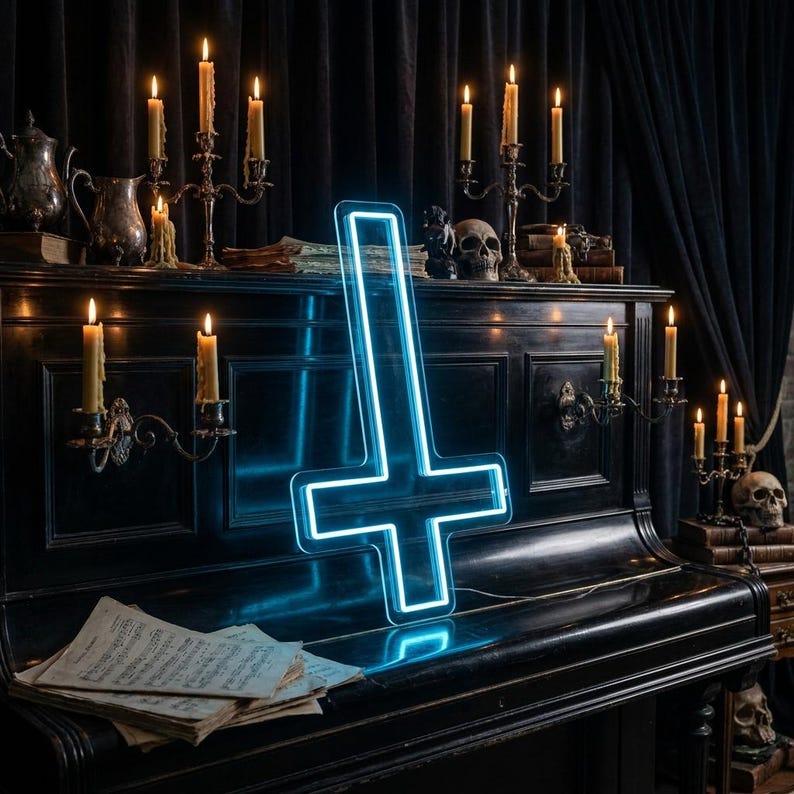 May include: A neon blue inverted cross sign is displayed on a black piano. The sign is illuminated with a bright blue light. The piano is surrounded by lit candles in antique candle holders, skulls, and sheet music, creating a gothic aesthetic.