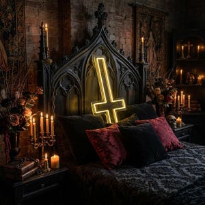 May include: A gothic-style bedroom with a black bed frame and a neon yellow inverted cross. The bed is adorned with black and red velvet pillows and a patterned comforter. Lit candles and floral arrangements add to the dark aesthetic.
