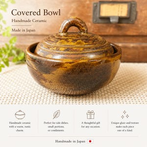 May include: A handmade ceramic covered bowl featuring a glossy, mottled brown and ochre glaze. The bowl has a rounded body and a matching lid with a small, arched handle on top. The text "Covered Bowl", "Handmade Ceramic", and "Made in Japan" is visible.