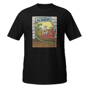 May include: Black t-shirt featuring a colorful illustration. The graphic depicts a lizard, mice, and other characters in a room with the text "EL-RINCON" on a sign. The shirt is made of a soft material.