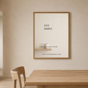 以下が含まれることがあります： LIVE SIMPLY, keep what matters, let the rest be light, LAGOM - a Swedish philosophy of enough というテキストが書かれた額縁入りのウォールアート。クリーム色の背景に、2つの白い陶器のボウルが置かれた小さな木製の棚が描かれています。
