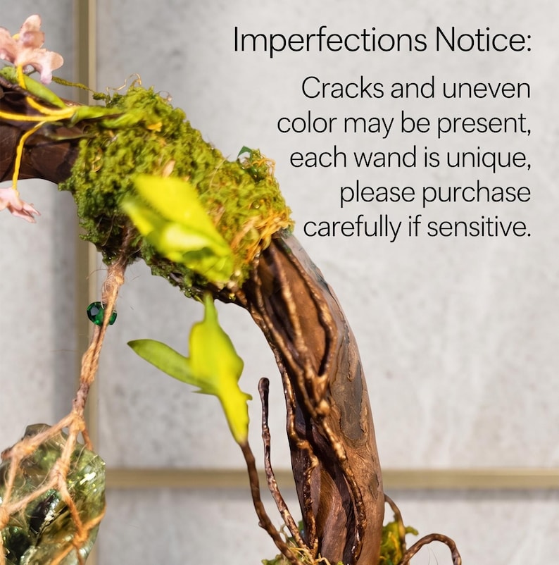 May include: A close-up of a decorative wand with a wooden branch base, adorned with green moss, yellow leaves, and small pink flowers. The wand has a natural, rustic appearance. Text on the image reads: "Imperfections Notice: Cracks and uneven color may be present..."