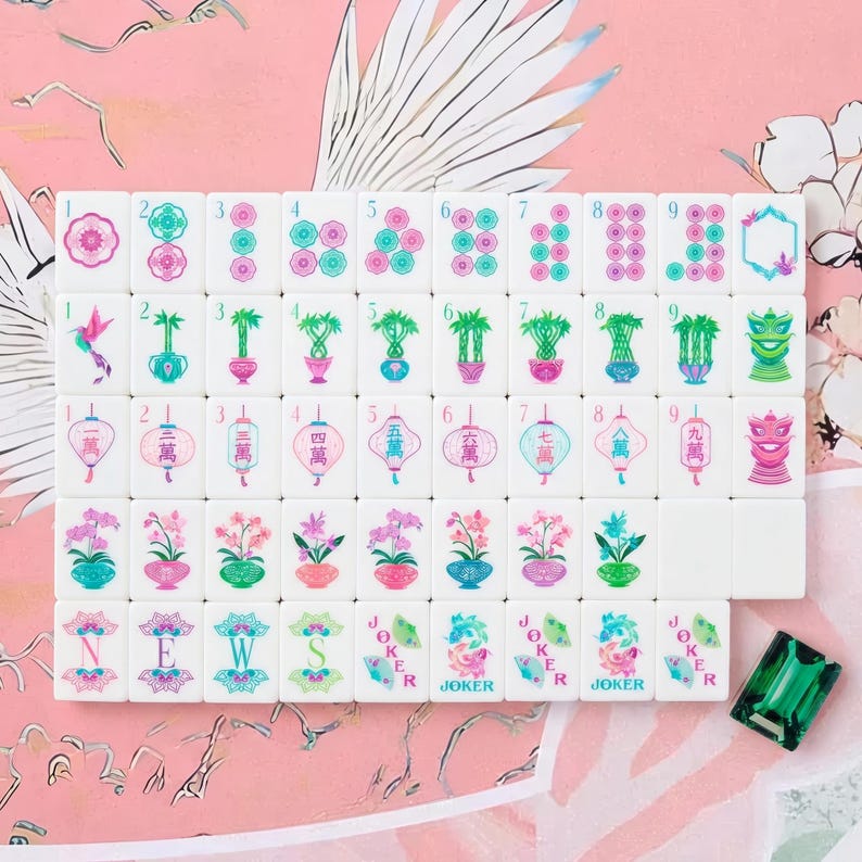 May include: A set of white mahjong tiles featuring colorful floral, bamboo, lantern, and character designs in pink, green, and blue. The tiles include numbered sequences, directional markers, and joker tiles, accompanied by a single green gem tile.