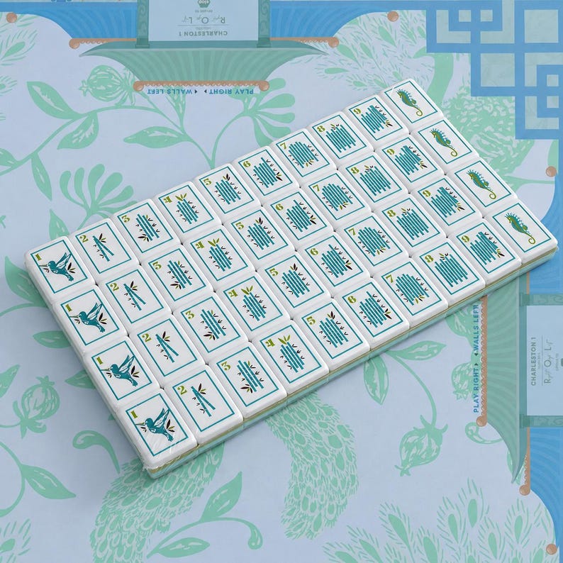 Pode incluir: Um conjunto de pe&ccedil;as retangulares de mahjong dispostas numa grelha sobre uma superf&iacute;cie azul-clara com padr&otilde;es. As pe&ccedil;as brancas apresentam gr&aacute;ficos em tom cerceta de beija-flores, bambu e cavalos-marinhos, com n&uacute;meros verdes.