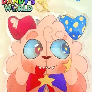 Puede incluir: Un llavero shaker de acrílico transparente con un personaje de dibujos animados con grandes ojos azules, lengua roja y una estrella amarilla en la mejilla. El personaje lleva un lazo rojo y azul con una estrella. Texto: GOOB 4 INCH EYE SHAKER KEYCHAIN y DANDY'S WORLD.