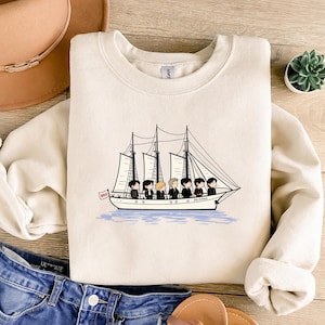 Puede incluir: Una taza de cerámica blanca con un asa negra y el texto "But First, Coffee" en negro y negrita. La taza está sobre una superficie de madera. La taza mide 10 cm de alto.