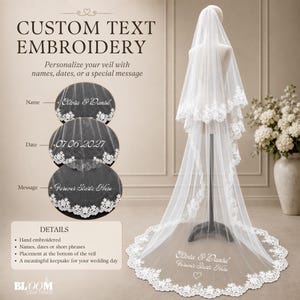 May include: A white, multi-layered wedding veil featuring intricate lace trim along the edges. The veil is displayed on a mannequin and includes custom embroidery at the bottom with the text Olivia & Daniel, Forever Starts Here, and a heart.