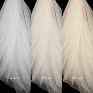 May include: A side-by-side comparison of three sheer tulle veils in different shades. The left veil is labeled WHITE, the center veil is labeled IVORY, and the right veil is labeled CREAM. Each veil features soft, flowing layers of fine fabric.