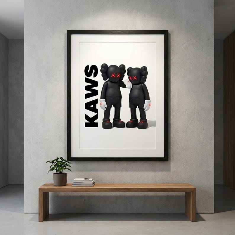 May include: Framed art print featuring two black figures with red 'X' eyes and hands, and red shoes. The word 'KAWS' is printed vertically in black. The artwork is displayed above a wooden bench with a small plant.