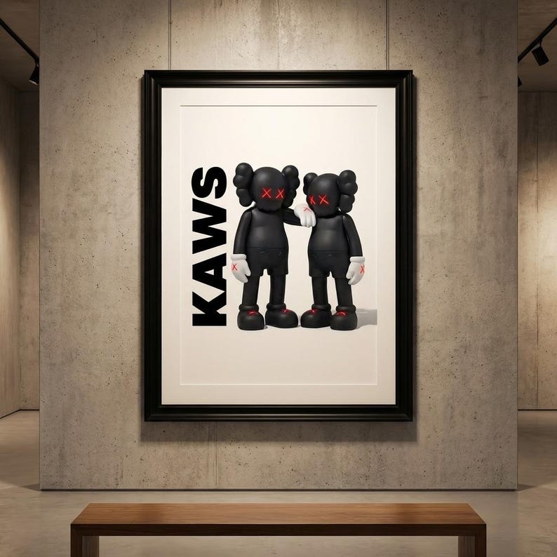 May include: Framed artwork featuring two black cartoon figures with red 'XX' eyes and white gloves, standing side-by-side. The word 'KAWS' is printed vertically in black on the left side of the artwork. The artwork is displayed in a gallery setting.