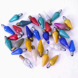 May include: A collection of vintage Christmas light bulbs in various colors, including red, blue, green, yellow, and white. The bulbs have a classic teardrop shape and metal bases, perfect for holiday decorating.