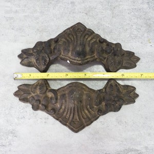 May include: Two antique cast iron drawer pulls with a floral design. The pulls are approximately 4 inches long.