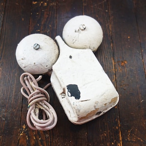 May include: White vintage telephone with two round bells and a coiled cord. The telephone is made of plastic and has a white finish. The bells are attached to the telephone by a metal arm.