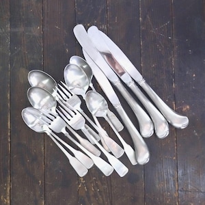 May include: A collection of silver-toned flatware including three dinner knives with smooth handles, three dinner forks with four tines, and four spoons of varying sizes. The utensils feature a polished metallic finish and simple, clean lines.