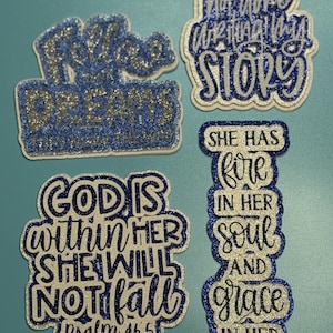 May include: Four glittery patches with blue and silver text. The patches read: Follow Your Dreams, God's Not Done Writing My Story, God Is Within Her She Will Not Fall Psalm 46:5, and She Has Fire In Her Soul And Grace In Her Heart.