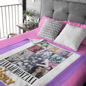 Pu&ograve; includere: Una coperta bianca e viola con un collage di immagini di Hannah Montana. La coperta ha un bordo viola ed &egrave; esposta su un letto con lenzuola e cuscini rosa. Il logo Disney &egrave; visibile.