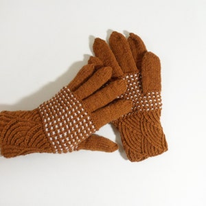 May include: A pair of brown knitted gloves with white accents. The gloves have a cable knit pattern on the cuff and a textured pattern on the palm.