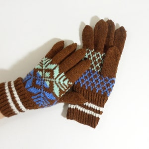 May include: A pair of brown knitted gloves with a blue, green, and white geometric pattern. The gloves have a brown and white striped cuff.