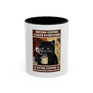May include: White ceramic coffee mug with a black interior. The mug features a graphic of a black cat holding a coffee cup, with text that reads "BEFORE COFFEE: I HATE EVERYONE" and "AFTER COFFEE: I FEEL GOOD ABOUT HATING EVERYONE."