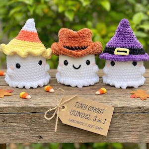 Puede incluir: Tres figuras de fantasmas de ganchillo hechas a mano, cada una con un sombrero único: un sombrero de caramelo de maíz, un sombrero de vaquero y un sombrero de bruja. Los fantasmas son blancos con ojos negros y caras sonrientes. Una etiqueta dice "Tiny Ghost Bundle: 3 in 1".
