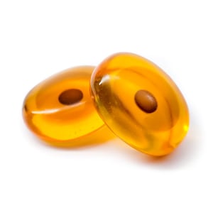 May include: Two amber glass beads with a small brown dot in the center of each bead.
