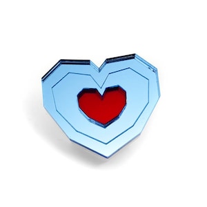 Puede incluir: Un pin de corazón azul con un corazón rojo en el centro. El corazón está hecho de múltiples capas de acrílico azul.