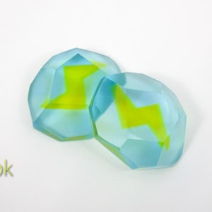 May include: Two light blue, faceted, glass gems with a yellow lightning bolt design.
