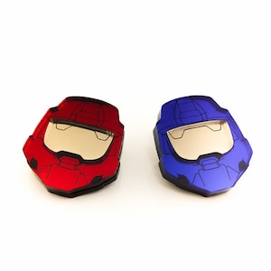 Pode incluir: Dois objetos em forma de capacete, um vermelho e outro azul, com viseira e design detalhado. Os capacetes s&atilde;o provavelmente inspirados em um videogame ou tema de fic&ccedil;&atilde;o cient&iacute;fica. Os objetos s&atilde;o exibidos em um fundo branco.