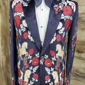 May include: Navy blue blazer with embroidered red flowers, white leaves, and gold horses and guitars. The blazer has a black velvet collar and lapel, and is paired with a white shirt and navy bow tie. A stylish formal wear.