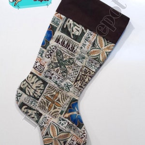 May include: A Christmas stocking with a brown cuff and a patterned body. The pattern features squares with floral and geometric designs in shades of green, blue, brown, and cream. The text "Bombshell Depot" is visible in the upper left corner.