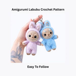 May include: Two amigurumi Labubu crochet dolls, one lavender and one light blue, with smiling faces and attached keychains. The dolls have a fuzzy texture and are wearing bunny-eared hoods. Text on the image reads "Amigurumi Labubu Crochet Pattern" and "Easy To Follow."