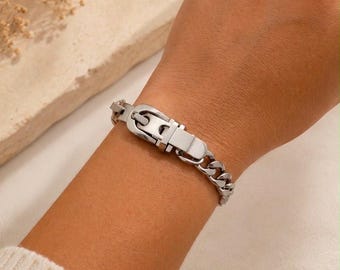 May include: A silver-toned metal chain bracelet featuring a central buckle-style clasp mechanism. The bracelet consists of interlocking polished links that form a continuous band, secured by a functional metal buckle closure in the center.