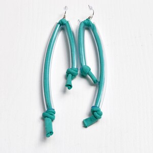 Peut inclure: Une paire de boucles d'oreilles bleu turquoise en tube de plastique transparent et en tissu. Le tissu est nou&eacute; en haut de chaque boucle d'oreille.